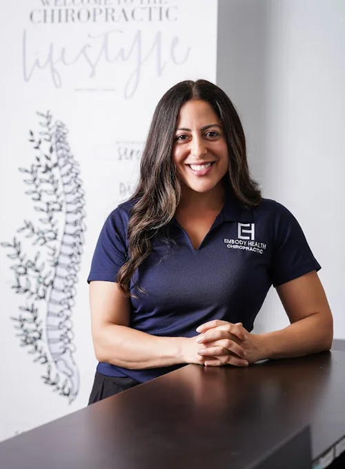 Dr. Nora Zoma posing with her hands on the front desk for a professional photo